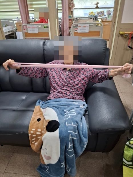 밴드를 양손으로 당기며 스트레칭하는 어르신