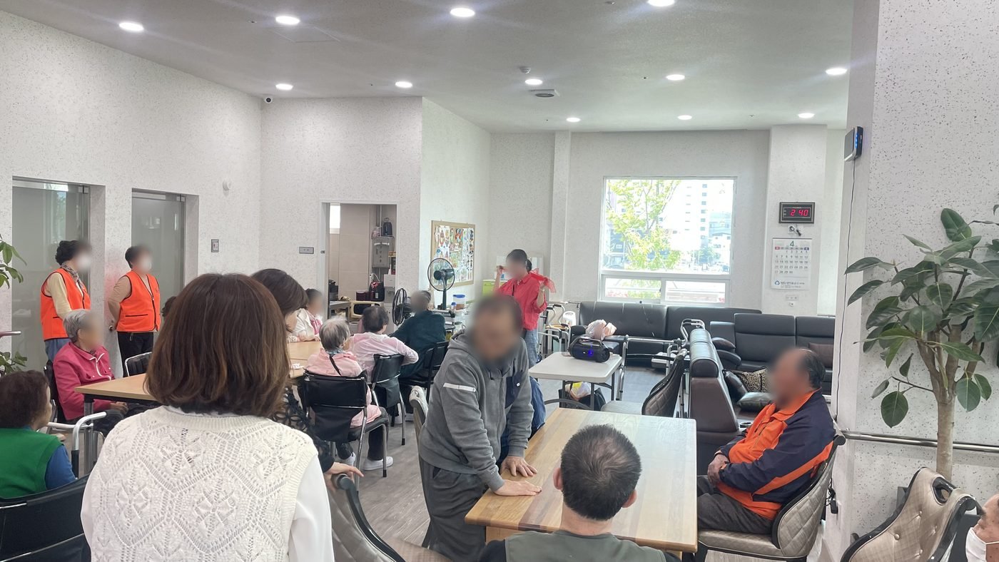 넓은 방에서 강사를 따라 함께 체조하는 어르신들
