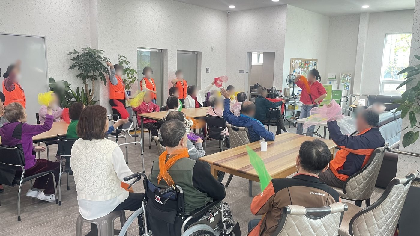 강사와 어르신들이 넓은 방에서 함께 체조하는 수업 현장