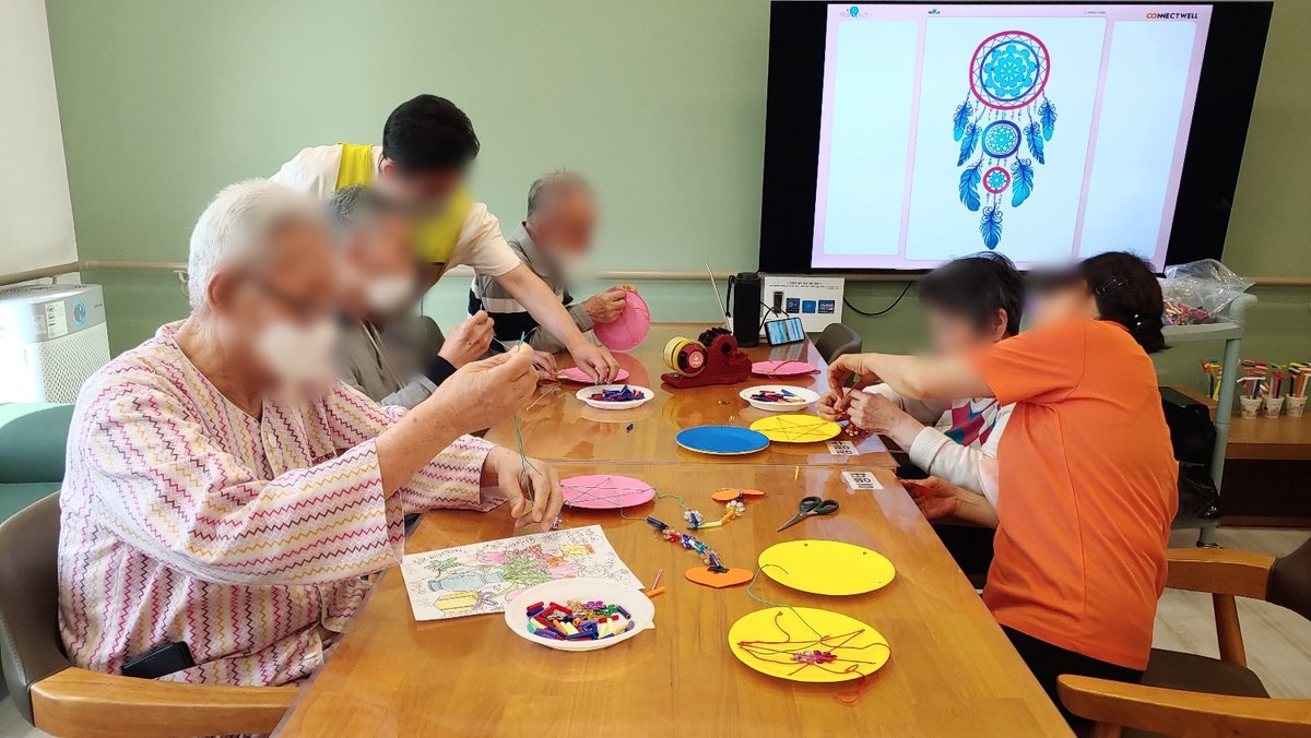 강사가 어르신들과 드림캐처 만들기를 하는 모습